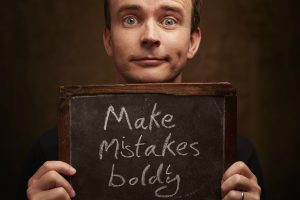 Image of storyteller and children's author Gareth P Jones holding a sign saying 'Make Mistakes Boldly'