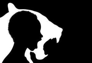 Black and white silhouette image of a person with their mouth open inside a silhouette of a lion roaring